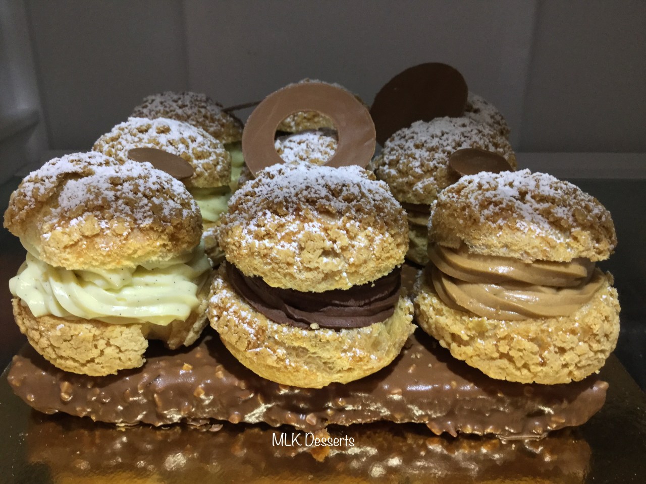Choux crème pâtissière vanille, crémeux praliné et chantilly chocolat sur un biscuit glaçage rocher